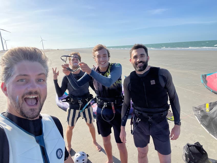 Quatre riders tout sourire sur la plage après un downwinder